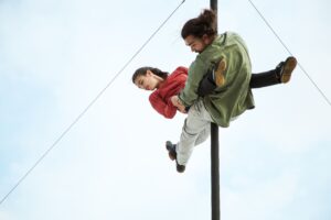 Les deux circassiens sont accrochés au mât chinois et on les jambes dans les airs.