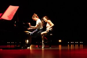 Les deux comédiennes sont assises sur le banc du piano.